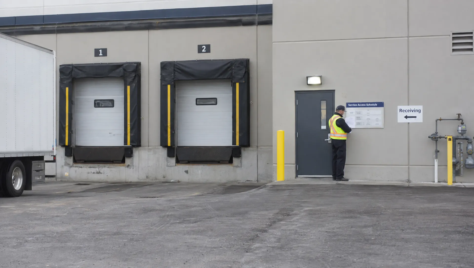 A facilities supervisor checks the service schedule at a commercial building entrance before arranging drain cleaning.